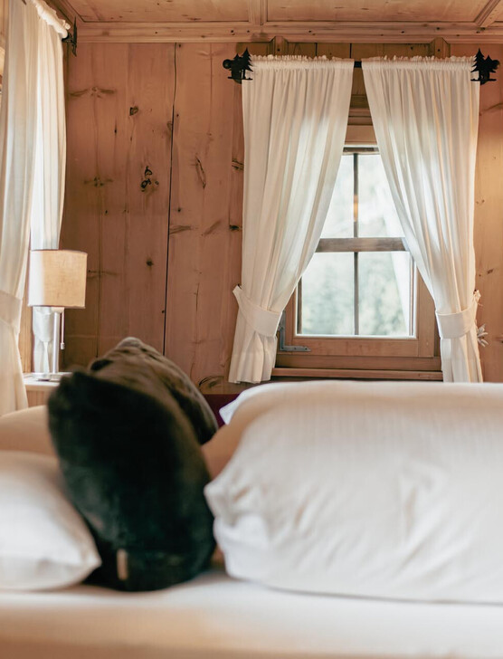 Gemütliches Schlafzimmer mit Holzwänden und weißen Vorhängen